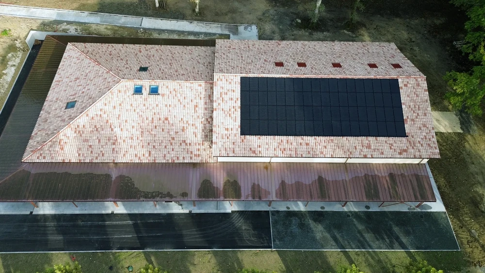 Vue aérienne d'un bâtiment industriel avec toiture en tuiles terre cuite équipée d'une installation photovoltaïque