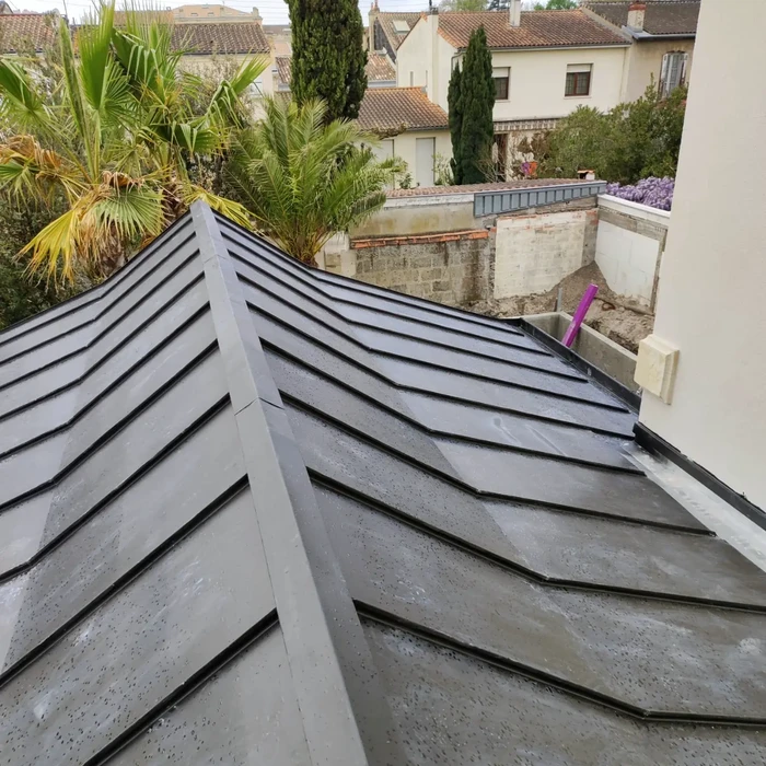 Toiture moderne en bac acier nervuré gris anthracite, vue plongeante sur faîtage et arêtier