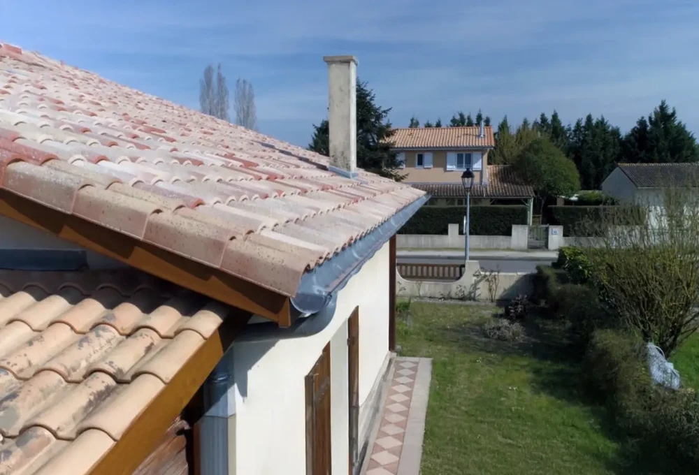 Scène extérieure montrant une toiture résidentielle avec tuiles canal en terre cuite de couleur rouge-orangé