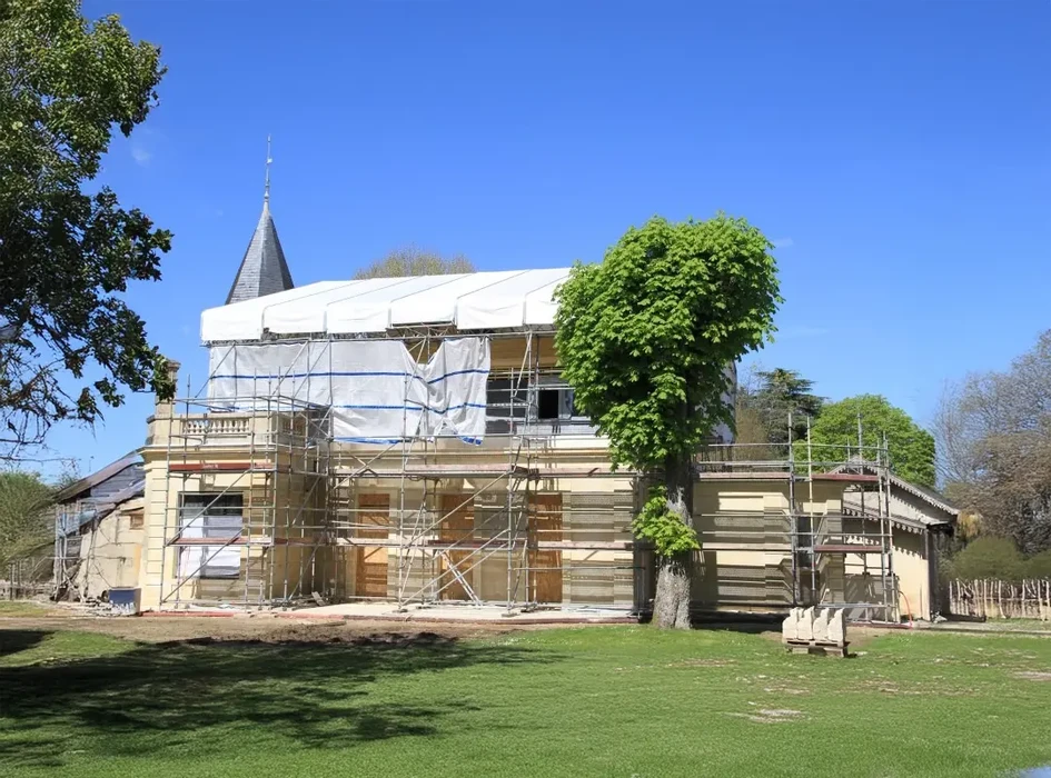 Chantier de rénovation d'un bâtiment historique en pierre avec tour conique