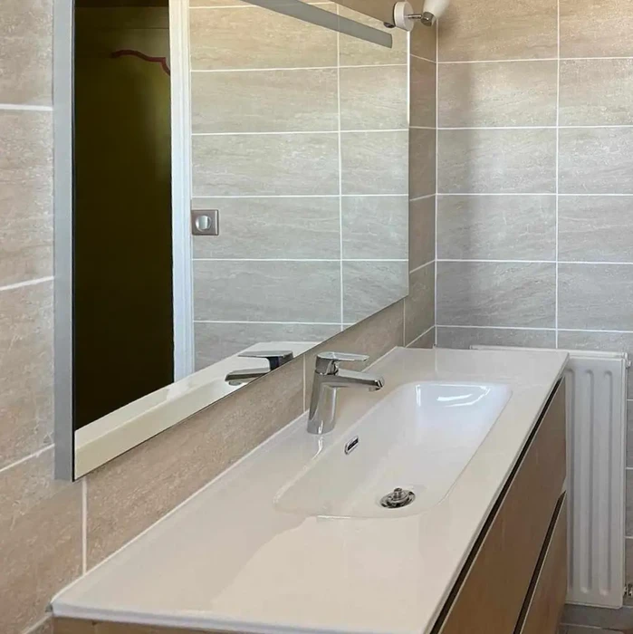 Salle de bain moderne luxueuse avec double vasque, baignoire encastrée près d'une baie vitrée donnant sur un paysage marin