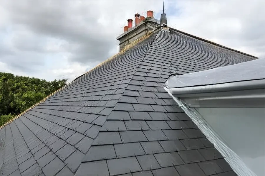 Vue extérieure d'une toiture en tuiles canal terre cuite avec installation de trois fenêtres de toit type Velux à ouverture par rotation