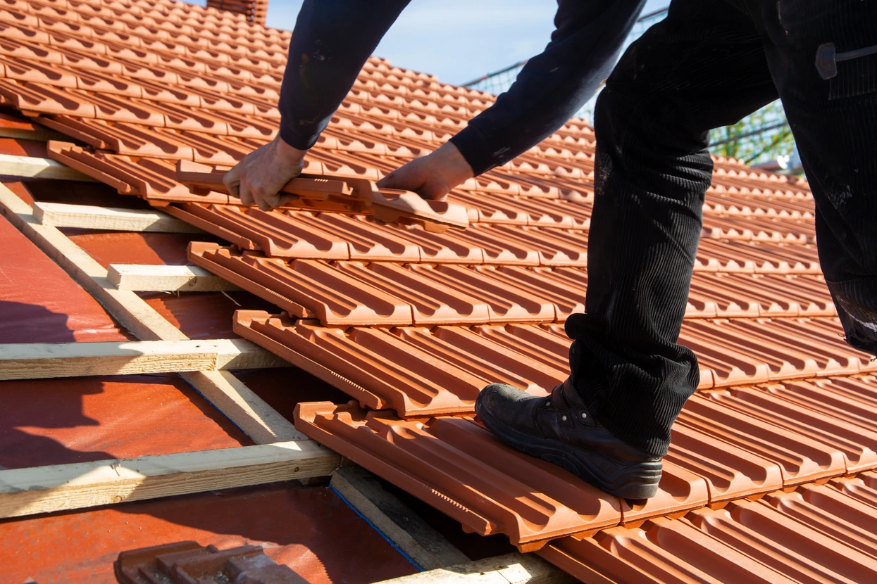 Toiture en tuiles d'argile rouge avec cheminées en béton rose équipées de chapeaux anti-refoulement