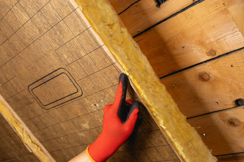 Homme installant une couche d'isolation thermique du toit &agrave; l'aide de laine min&eacute;rale