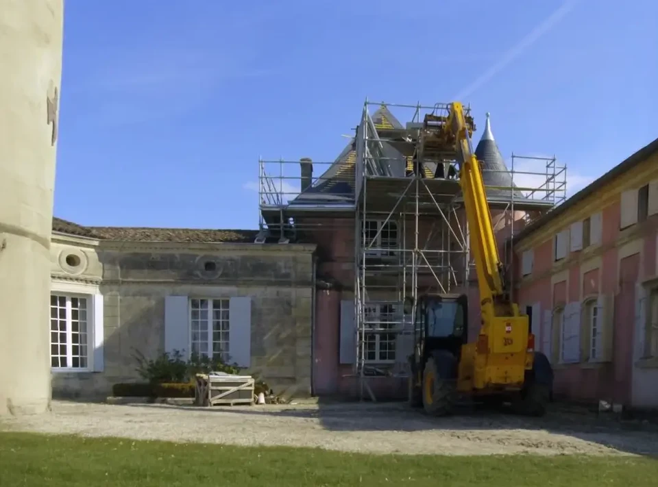Chantier de toiture extérieur, ouvrier couvreur en vêtements de travail et gants noirs installant des tuiles terre cuite sur charpente